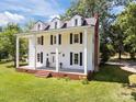 Classic white facade featuring dormer windows, black shutters, and inviting front porch with white support columns at 550 Woodleaf Barber Rd, Cleveland, NC 27013