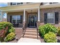 Inviting front entrance featuring brick steps, white columns, a decorative front door, and manicured landscaping at 7355 Drury Ln, Denver, NC 28037