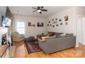 A cozy living room showcasing hardwood floors, a ceiling fan, a fireplace, and a comfortable gray sectional at 9410 Culcairn Rd, Huntersville, NC 28078