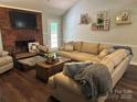 Comfortable living room with a brick fireplace, neutral sofa, and hardwood floors at 3210 Crow Row, Monroe, NC 28112