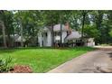 Two-story home with a lush front lawn, tall trees, and a long driveway leading to a garage at 9424 Whitethorn Dr, Charlotte, NC 28277