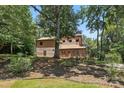 Exterior showcasing natural landscaping and a rustic wood facade shaded by mature trees on a sunny day at 1119 Palmyra Dr, Fort Mill, SC 29708