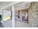 Welcoming covered front porch with stone facade, entry door with glass and white doorframe at 15120 Cavanshire Trl, Charlotte, NC 28278