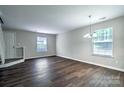 Bright living room with dark floors, neutral walls, a chandelier, and an entry to the staircase at 3919 Briarhill Dr, Charlotte, NC 28215