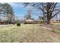 A single-story brick home with a well-manicured lawn and mature trees, offering a blend of comfort and nature at 4601 Mendham Dr, Charlotte, NC 28215