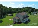 Aerial view showcasing a two-story home, large yard, outbuilding, and surrounding trees at 550 Baker Mill Rd, Cleveland, NC 27013