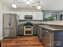 Bright kitchen showcasing stainless steel appliances, granite countertops, stylish cabinetry, and hardwood floors at 7024 Sunman Rd, Charlotte, NC 28216