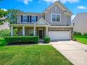 Inviting two-story home featuring a classic design, a front porch and lush green lawn at 10409 Dominion Village Dr, Charlotte, NC 28269