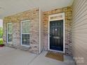 Welcoming front door with brick facade, sidelight windows, and a cozy doormat at 10409 Dominion Village Dr, Charlotte, NC 28269