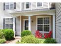 Close up of inviting front porch with black door, bright red chairs, and lush landscaping at 12341 Mcallister Park Dr, Charlotte, NC 28277