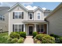 Inviting front porch with black door, bright red chairs, and lush landscaping at 12341 Mcallister Park Dr, Charlotte, NC 28277