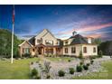 Elegant brick home with a welcoming front porch, manicured lawn, and a picturesque American flag at 1430 Rosehill Dr, Waxhaw, NC 28173