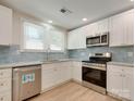 Bright kitchen featuring white cabinets, stainless appliances, and a stylish backsplash at 2414 Lane St, Kannapolis, NC 28083