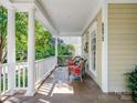 Relaxing front porch with classic columns, seating, and views of the lush, green neighborhood at 5572 Yorke Nw St, Concord, NC 28027
