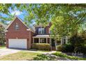 Charming two-story brick home with a covered porch and attached two-car garage, showcasing curb appeal at 6800 Augustine Way, Charlotte, NC 28270
