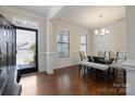Bright dining room with hardwood floors, white trim, glass table, chandelier, and a view through the front door at 12704 Franklin Square Rd, Charlotte, NC 28213