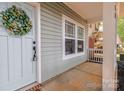 Close-up of the inviting front porch with a decorative wreath on the front door and a charming welcome mat at 13115 Meadowmere Rd, Huntersville, NC 28078