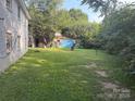 Spacious backyard with a storage building, surrounded by lush trees and foliage, offering privacy at 2103 Clawson Ave, Kannapolis, NC 28081