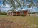 Brick home with a covered porch, manicured bushes, and expansive yard, radiating classic charm at 3113 Old Pageland Marshville Rd, Wingate, NC 28174