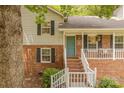 Inviting front porch with brick steps, white railings, black shutters, and a teal front door with decorative wreath at 6418 Tivoli Ct, Charlotte, NC 28211