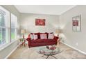 Bright living room with a comfortable red sofa, glass coffee table, and tasteful decor at 7339 Dover Mill Sw Dr, Concord, NC 28025
