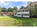 Exterior view of a two-story home with black shutters on a green lawn, next to a brick home and car at 80 Lecline Ne Cir, Concord, NC 28025