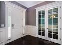 Elegant foyer featuring dark hardwood floors, white wainscoting, and a front door with sidelights at 8402 Aspen Ct, Charlotte, NC 28227
