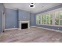 Bright living room with a fireplace, large windows, and light hardwood floors at 8402 Aspen Ct, Charlotte, NC 28227