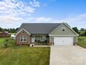 Lovely exterior view of the home featuring a green lawn, brick facade, and attached two car garage at 100 Royal Ave, Albemarle, NC 28001