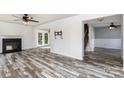 Open living room featuring new floors, a ceiling fan, a fireplace, and access to another room at 12250 Wallace Ridge Dr, Charlotte, NC 28269