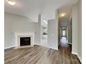 Bright, open-concept living room with fireplace, wood floors, and a glimpse into the adjacent kitchen and hallway at 1703 Southwind Dr, Charlotte, NC 28216