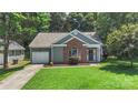 Home with a manicured lawn, brick accents, attached garage, and mature trees at 3212 Ashwell Oaks Ln, Matthews, NC 28105