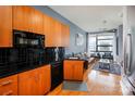 Open kitchen with wood cabinets, black countertops, and a view of the living area at 525 E 6Th St, Charlotte, NC 28202