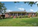 Charming brick home featuring a covered front porch, manicured lawn, and classic architectural details at 3381 Elaine Ave, Lincolnton, NC 28092