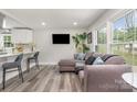 Open-concept living room features a comfortable sectional sofa, hardwood floors, and large windows with natural light at 8208 Doverdale Ln, Charlotte, NC 28217
