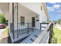 Inviting porch features dark trim, modern railing design, and a covered entrance with address number at 105 Mcgill Nw Ave, Concord, NC 28025
