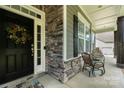 Inviting front porch with seating, a welcoming wreath, and stone accents at 1320 Torrens Dr, Wesley Chapel, NC 28110