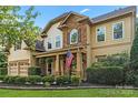 Beautiful two-story home with a stone facade, a manicured lawn, and an inviting front porch at 1800 Robbins Meadows Dr, Waxhaw, NC 28173