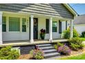 A covered front porch with black shutters, columns, colorful flowerbeds, and black steps enhance the entry at 903 Rhode Island Ave, Kannapolis, NC 28083