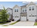 Townhouse exterior with light gray siding, stone accents and white garage doors at 13323 Savaine St, Charlotte, NC 28278