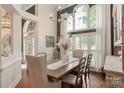Bright dining room with hardwood floors, large windows, white drapes, and an elegant chandelier at 3003 Wedge Ct, Matthews, NC 28104