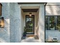 Close-up of the home's front door with black trim, decorative light fixture and 'welcome' mat at 4349 Castleton Rd, Charlotte, NC 28211