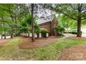 Manicured backyard with mature trees, lush lawn, and a charming brick exterior, creating a serene outdoor space at 5205 Tedorill Ln, Charlotte, NC 28226