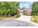 Charming brick home featuring a well-manicured lawn and a spacious driveway leading to an attached garage at 5205 Tedorill Ln, Charlotte, NC 28226