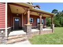 Inviting front porch with stone accents, wooden pillars, and a cozy seating area at 670 Cricket Ln, Mt Ulla, NC 28125