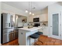 Modern kitchen boasts stainless steel appliances, a center island with seating, and bright white cabinetry at 10094 Treeside Ln, Matthews, NC 28105