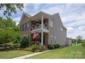 Two-story home features a brick and siding exterior, double porch, American flag, and manicured lawn at 10818 Alvarado Way, Charlotte, NC 28277