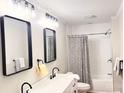 Modern bathroom with double vanity, sleek mirrors, and a stylish shower/tub combo with patterned curtain at 210 W Church St, Cherryville, NC 28021