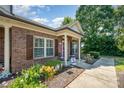 Inviting brick home with a cozy front porch, flower beds, and well-maintained lawn at 2773 Clover Nw Rd, Concord, NC 28027