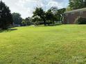 Expansive backyard with lush green grass and a few mature trees with the brick house in the background at 3009 Grier St, Newton, NC 28658
